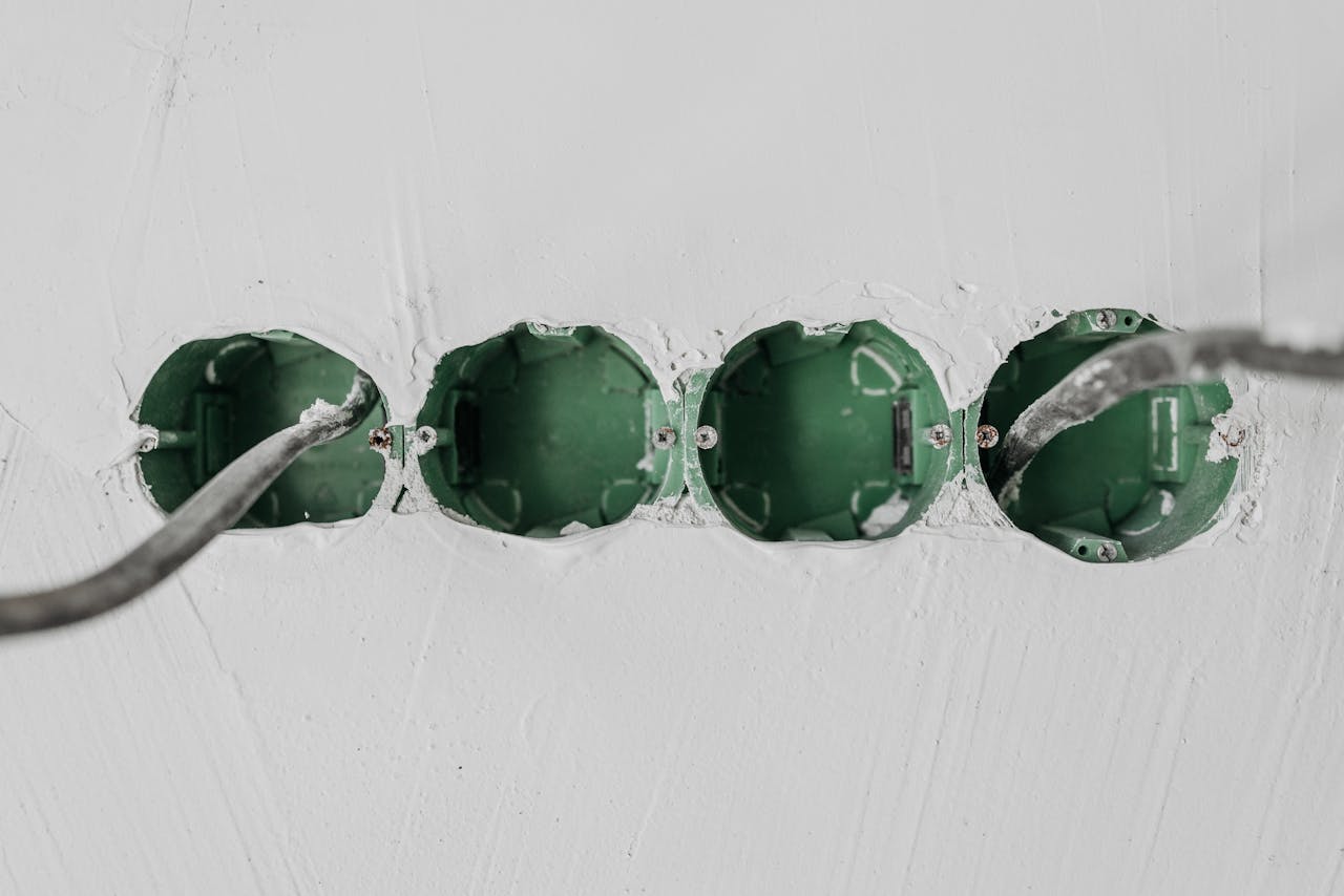 Close-up of green electrical boxes and wiring in a wall setup.